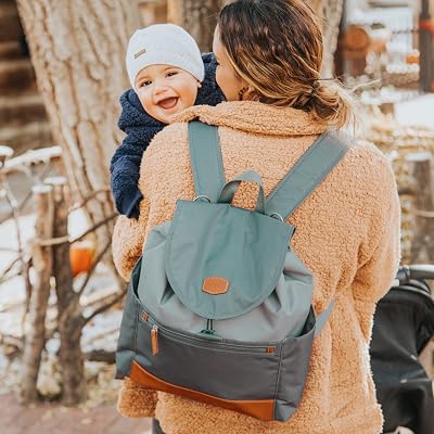 A parent carrying a baby, wearing a JJ Cole backpack diaper bag